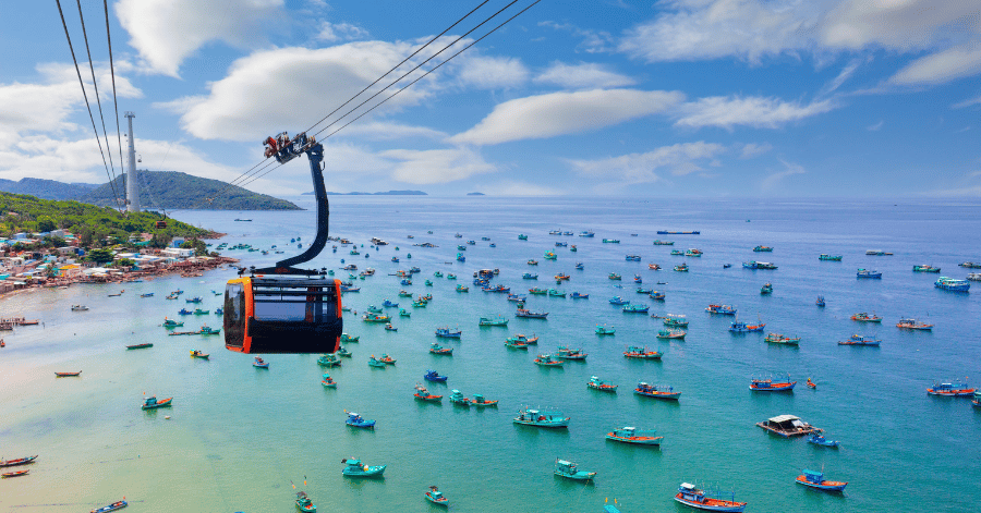 Hon Thom cable car gondola gliding over a turquoise bay full of fishing boats, Phu Quoc