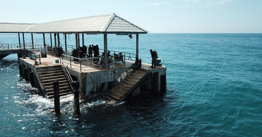 People on a covered jetty platform above clear blue water on Tioman