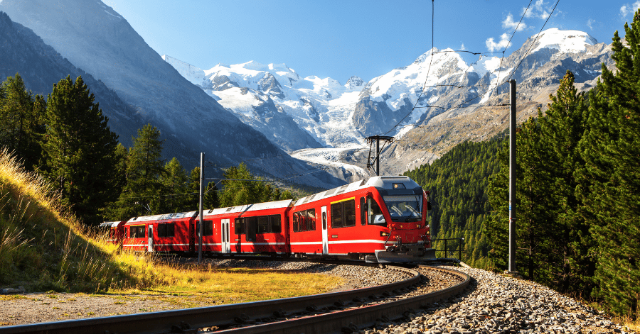 A red Swiss alpine train winding along a mountain track past a glacier and snow-capped peaks