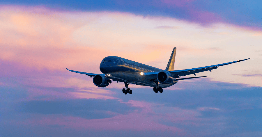 A passenger jet coming in to land against a pink and purple dusk sky