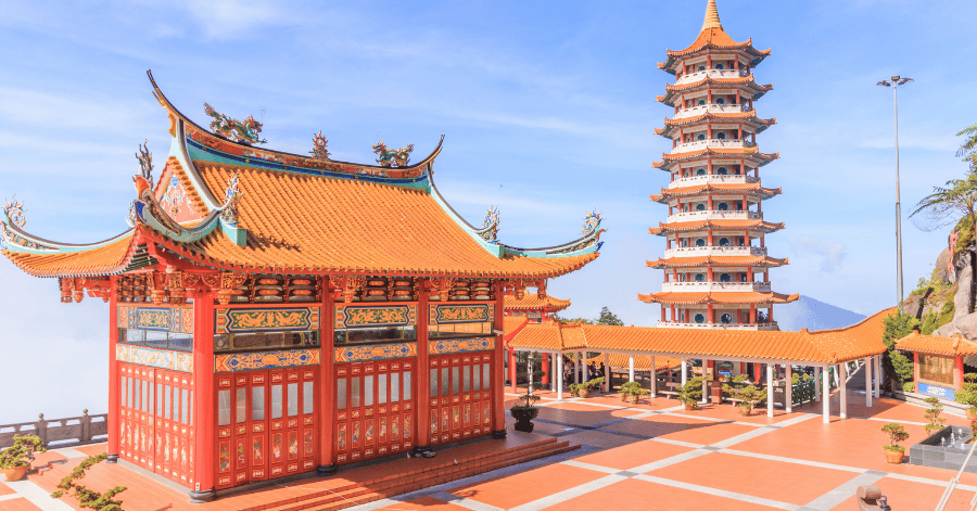 Ornate red-and-gold temple pavilion and pagoda at Genting under a blue sky