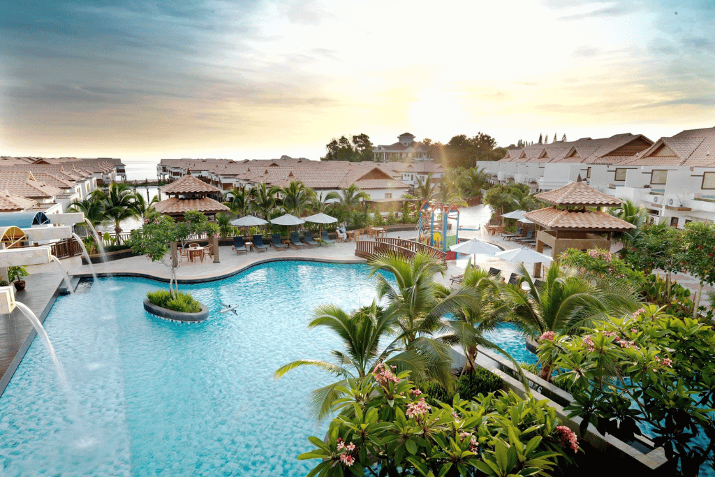 Resort swimming pool with loungers and palm trees at sunset