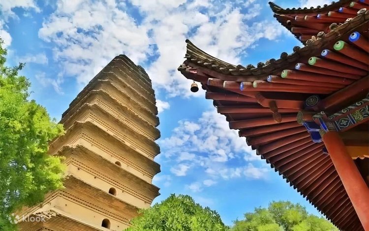 The brick Small Wild Goose Pagoda beside a temple eave under a blue sky