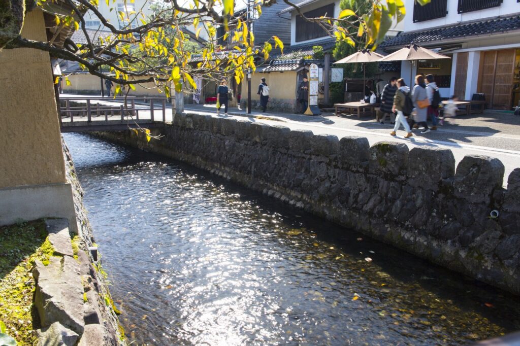 Stone-lined canal running beside a street of old houses and cafes in Kanazawa