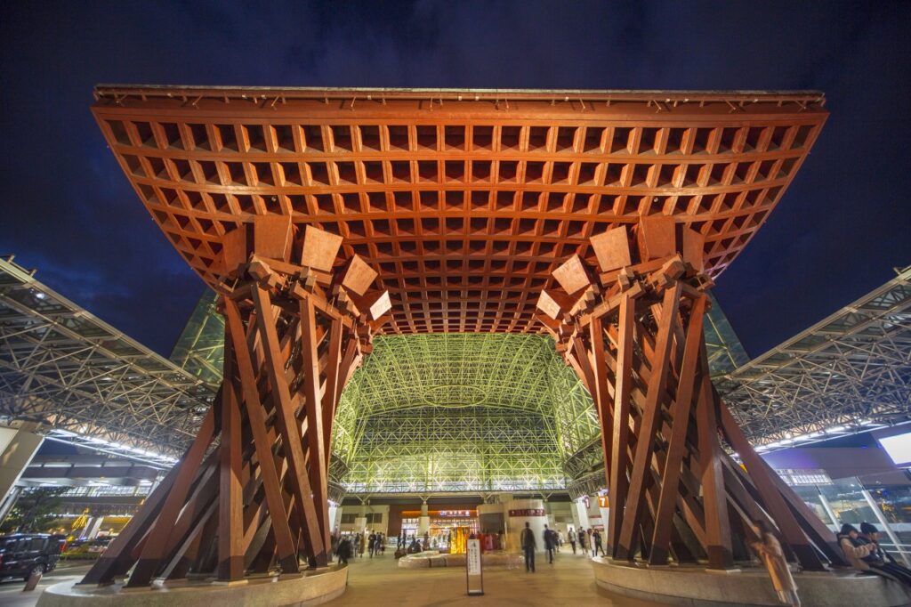 The wooden Tsuzumi-mon drum gate lit up at night outside Kanazawa Station