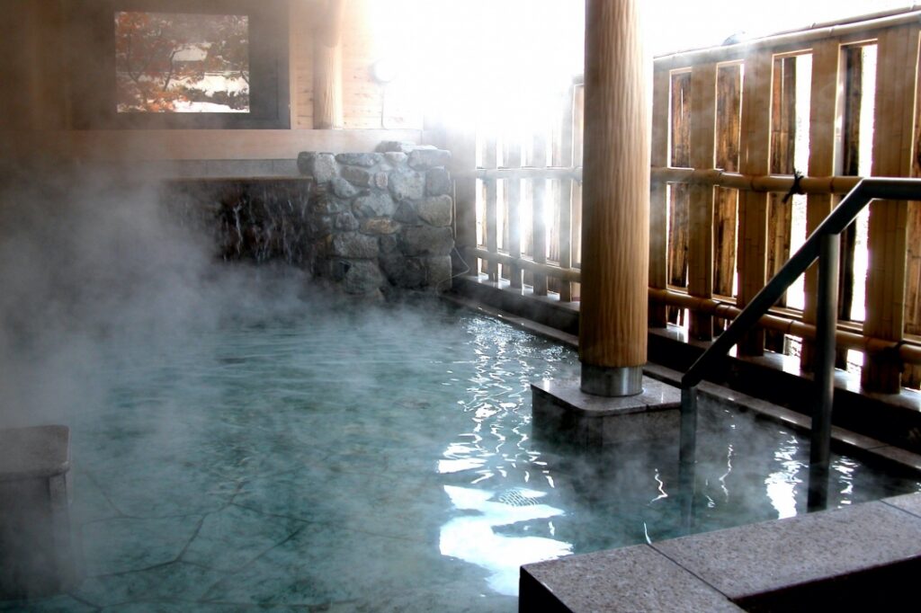 Steam rising over the stone-and-bamboo hot-spring bath at Shirakawa-go no Yu