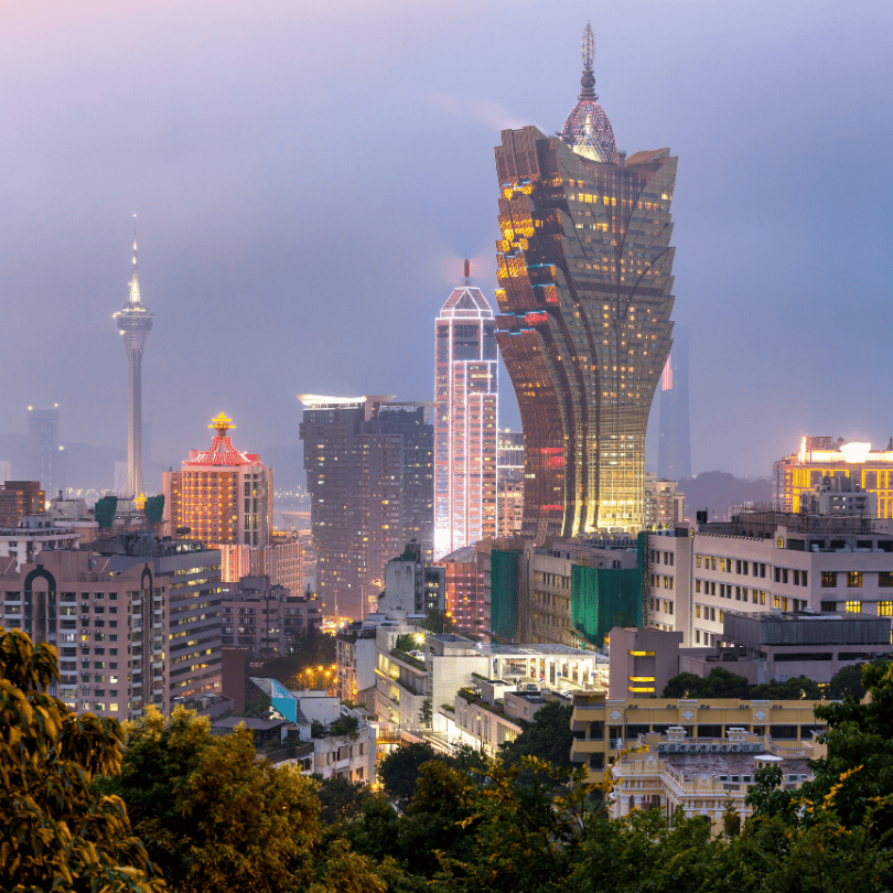 Macau's misty dusk skyline with the illuminated Grand Lisboa tower and distant Macau Tower