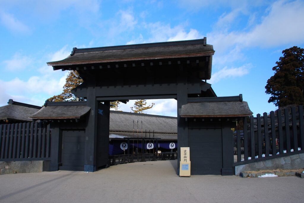 The black wooden main gate of the reconstructed Hakone Checkpoint under a blue sky