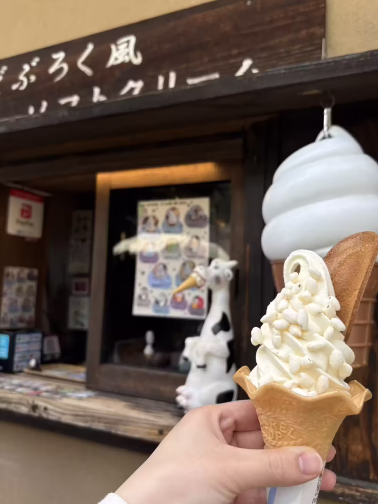 A doburoku-flavoured soft-serve cone topped with puffed rice, held outside a Shirakawago shop