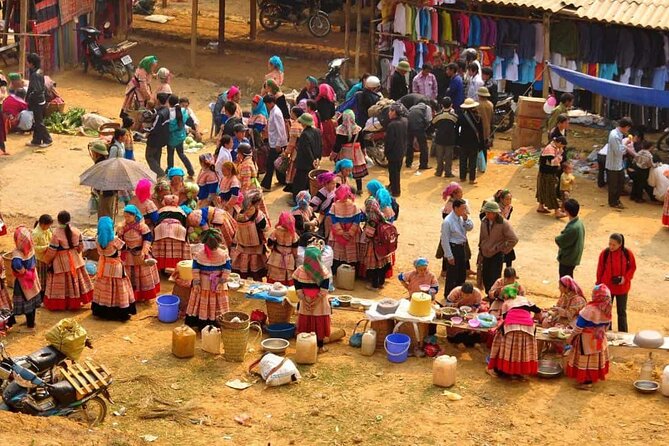 Flower H'mong traders in traditional dress gathered at a busy outdoor upland market near Sapa