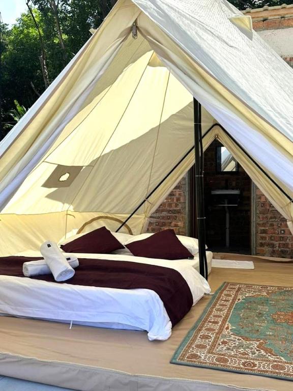 Interior of a canvas glamping bell tent with a made-up double bed and a patterned rug