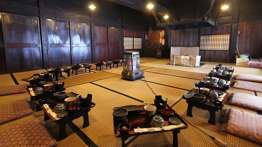 Low tables set with a traditional meal in the tatami dining hall of a gassho-zukuri inn