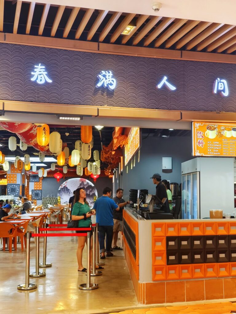 The Chun Man Ren Jian food court at R&F Mall, with hanging lanterns and an orange drinks counter