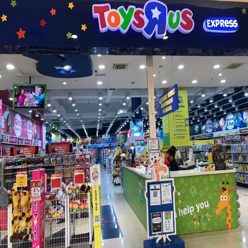 The colourful Toys R Us Express storefront and help desk with toy aisles behind