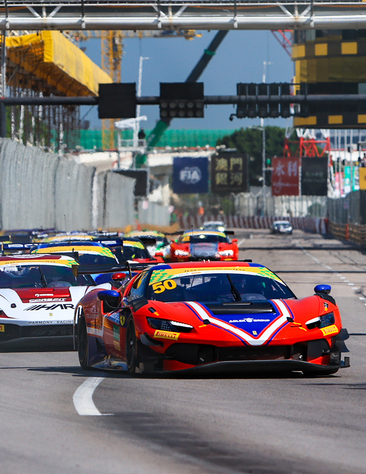 A red number 50 GT racing car leads the pack on the Macau Grand Prix street circuit