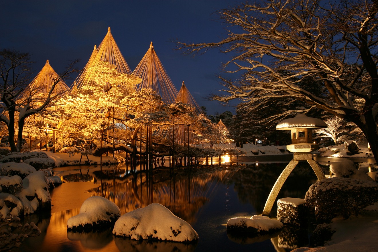 Kenroku-en Garden lit at night in winter, snowy pines with golden yukitsuri ropes