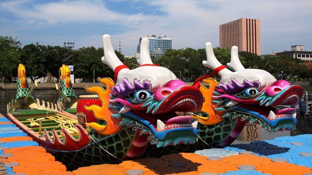 Ornately carved dragon-head boats moored on the water with Kaohsiung's skyline behind