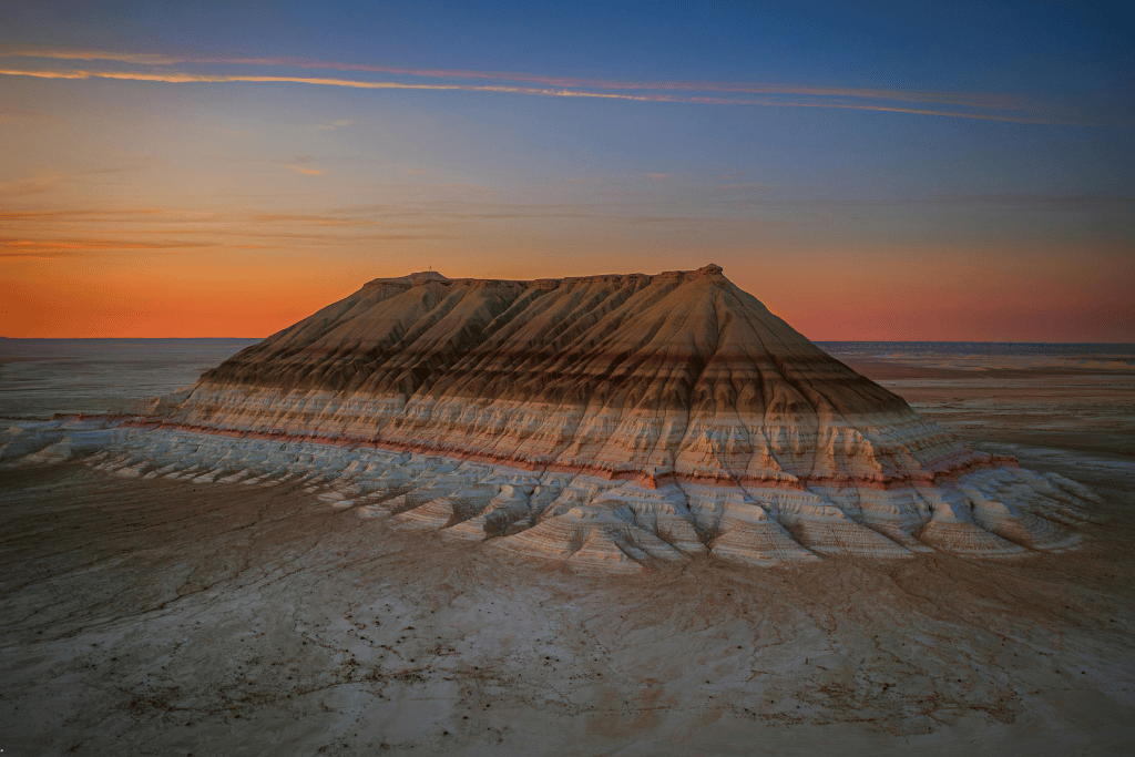 A flat-topped chalk mountain rising from the Mangystau desert at sunset