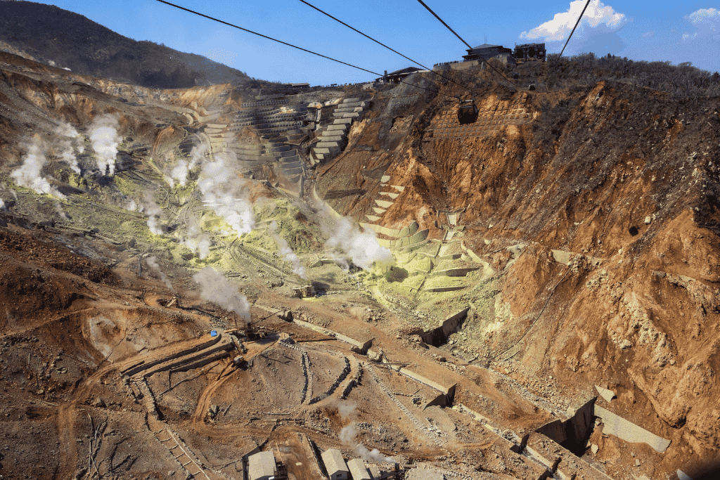 Bare orange sulphuric slopes and steam vents of Owakudani seen from a ropeway gondola