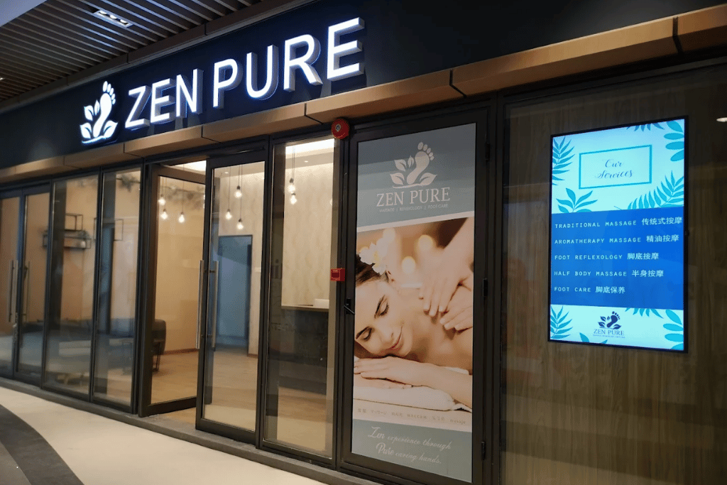 Zen Pure massage and reflexology shopfront at R&F Mall, with a services list lit up in the window