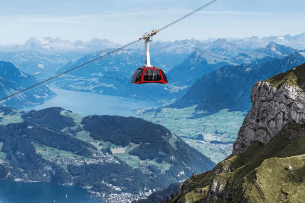 A red aerial cable car high above a lake and layered mountain ranges