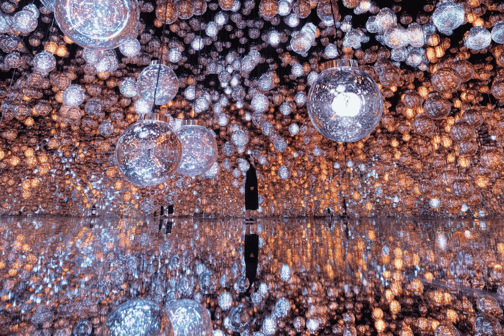 Visitors among glowing multicoloured light bars in a dark room at teamLab Borderless