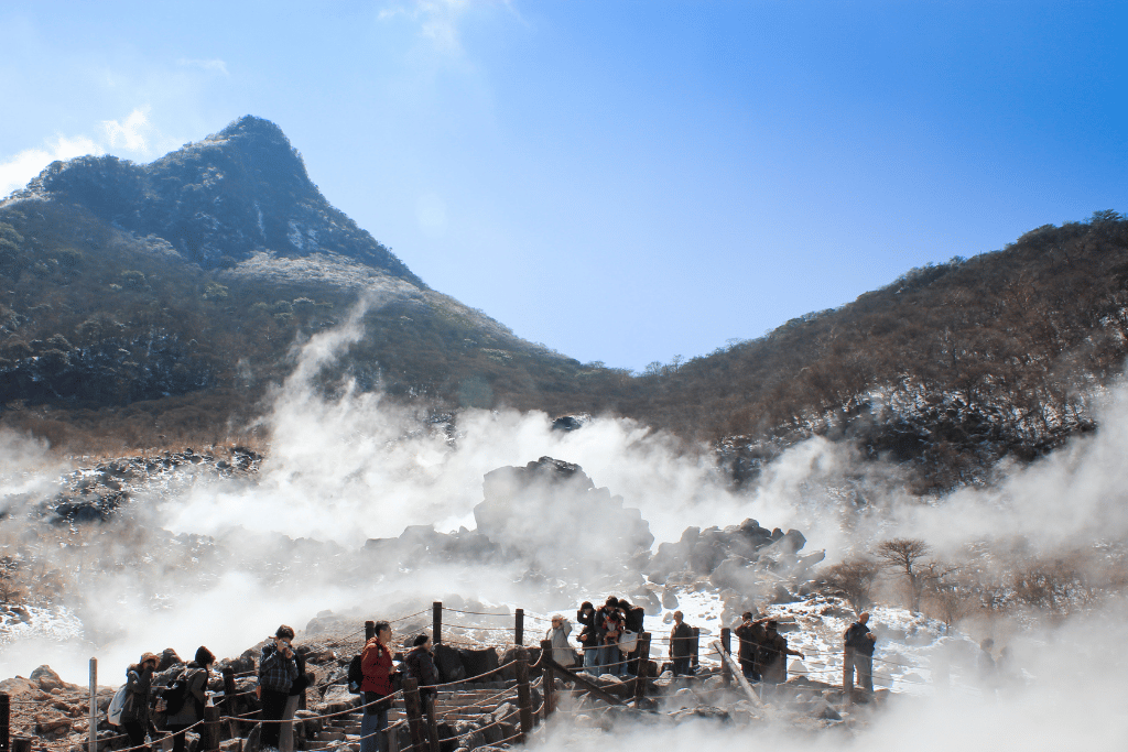 Visitors on a boardwalk among steaming volcanic vents at snow-dusted Owakudani