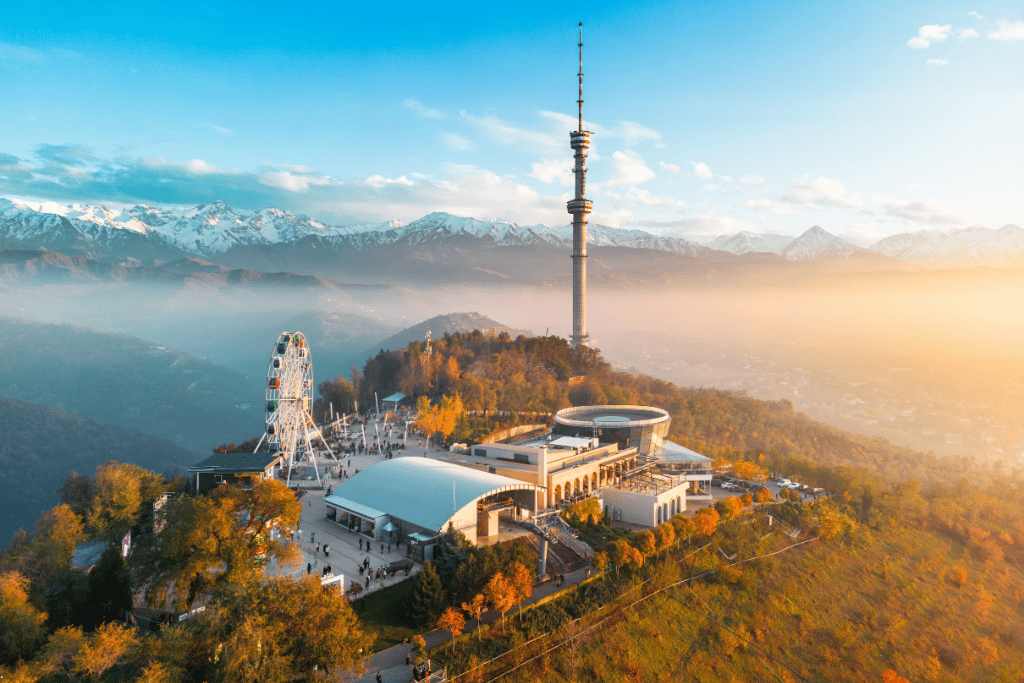Almaty TV Tower and a Ferris wheel on Kok-Tobe hill at golden sunset