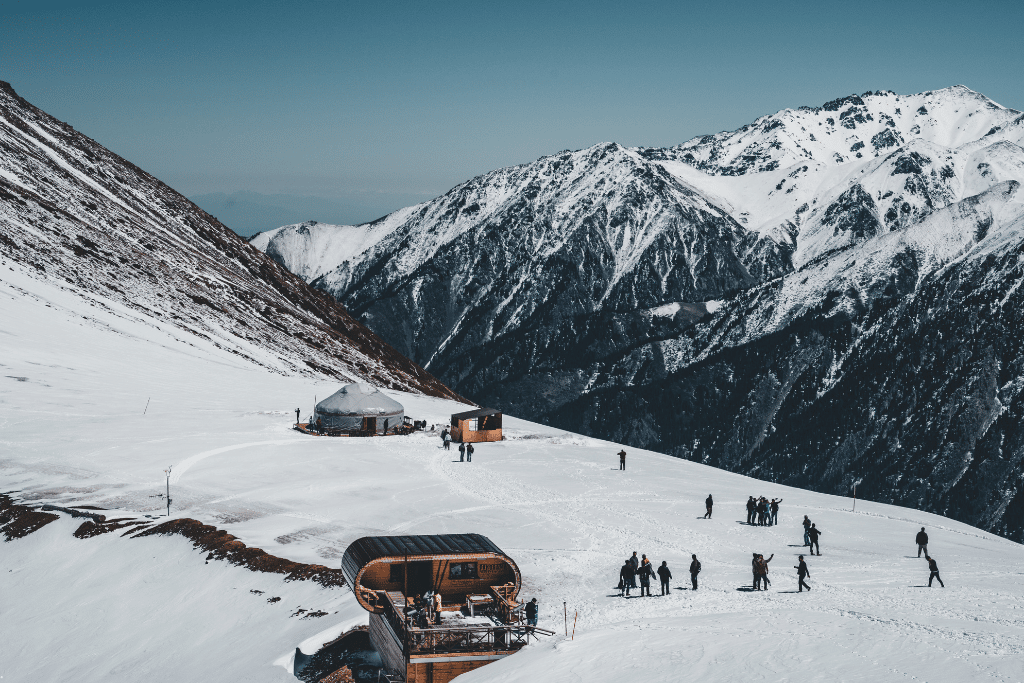 Snow-covered slopes and a yurt at Shymbulak, ringed by snow-capped peaks