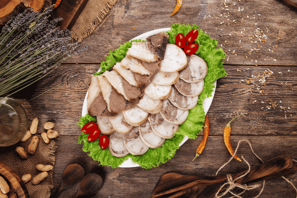 Slices of pale marbled kazy horse-meat sausage arranged on lettuce