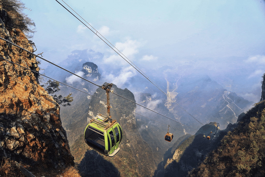 Cable-car gondolas over mist-shrouded Tianmen Mountain and its winding road