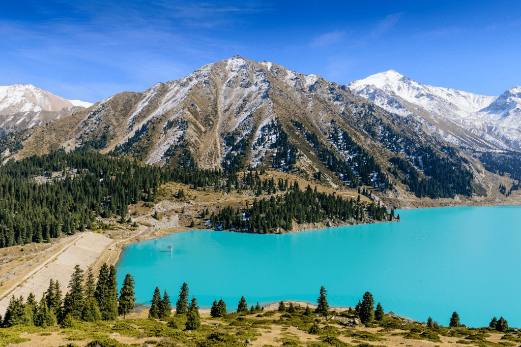 The turquoise water of Big Almaty Lake ringed by pine forest and peaks