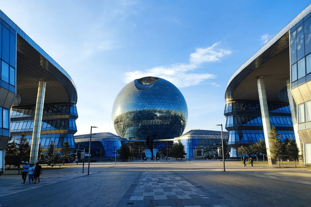 The mirrored glass Nur-Alem sphere flanked by curved Expo buildings in Astana