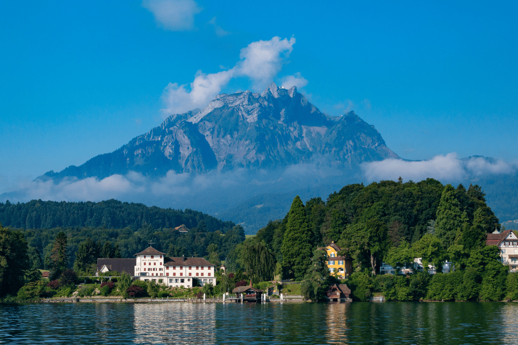 Mount Pilatus rising above Lake Lucerne, with a lakeside hotel among trees