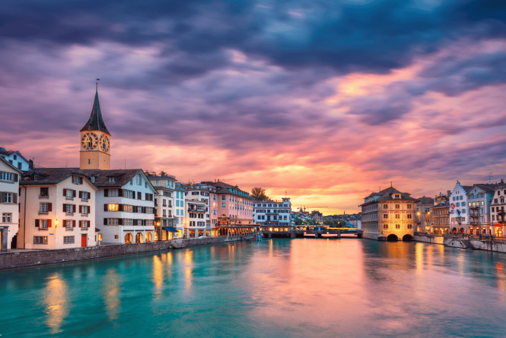 Zurich's old town and St Peter's clock tower along the Limmat river at sunset