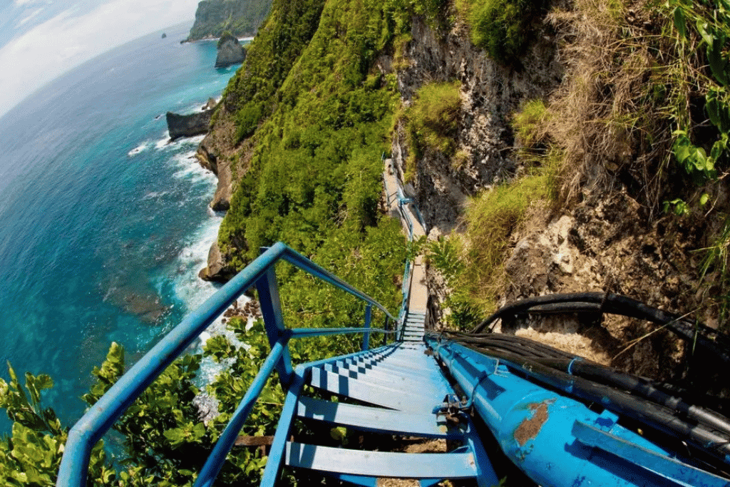 The steep blue-painted staircase clinging to the sea cliff on the descent at Peguyangan
