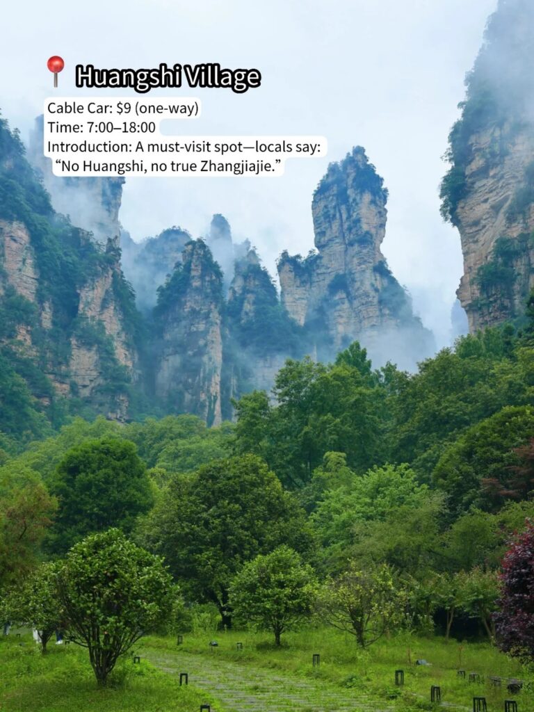 Mist-wrapped sandstone pillars above a green meadow at Huangshi Village, Zhangjiajie