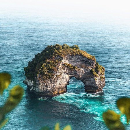 The arched sea-stack rock formation off Banah Cliff rising from deep blue water