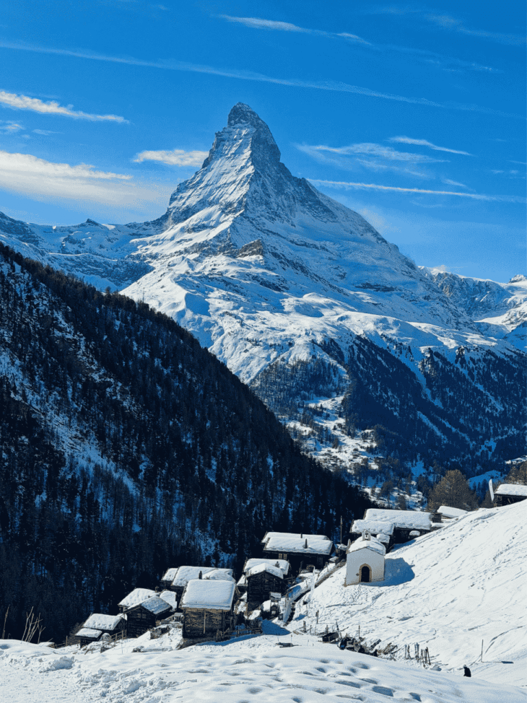 The Matterhorn towering over snow-covered wooden chalets and a small chapel