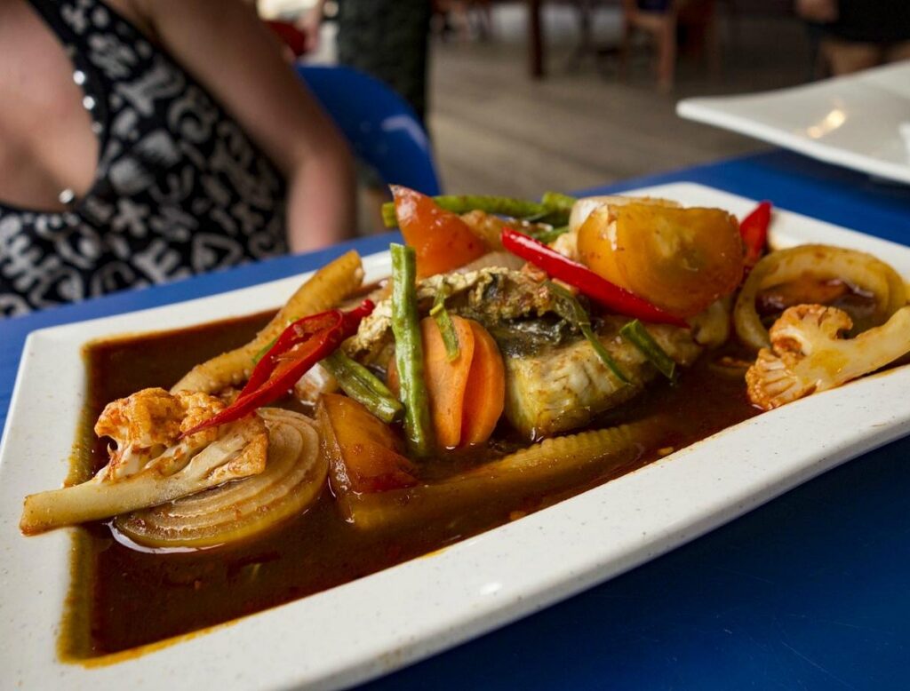 A plate of fish in sweet soy sauce with chilli, onion and vegetables at Ewan Cafe