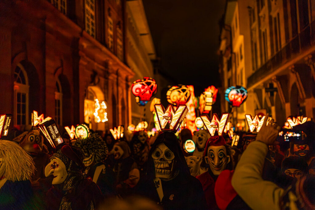 Masked revellers and glowing painted lanterns fill a street at Basel's Fasnacht carnival