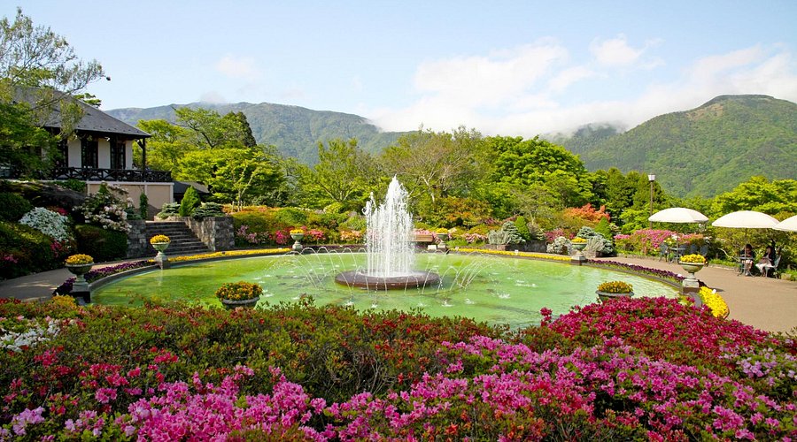 A formal fountain and beds of pink azaleas at Gora Park with mountains behind
