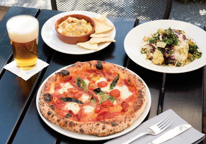 A wood-fired margherita pizza, a beer and sides on an outdoor table at GARDEN HOUSE Kamakura