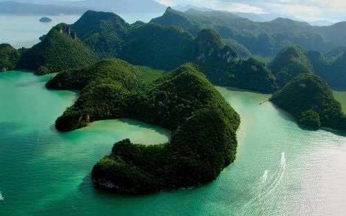 Aerial view of a curved forested island and lagoon in the Langkawi archipelago