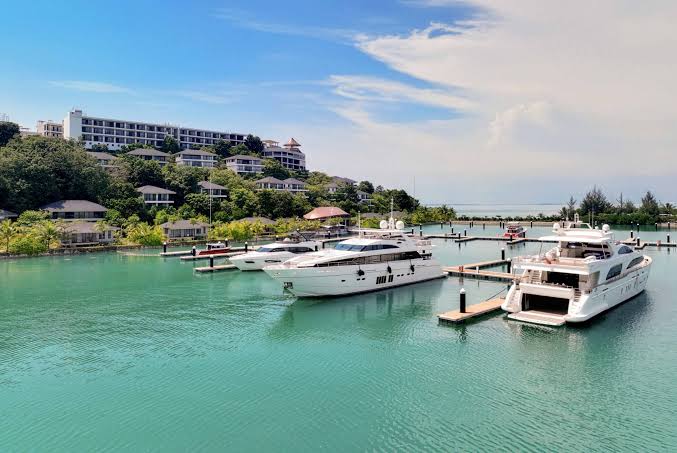 Luxury yachts moored at an island resort marina in calm green water