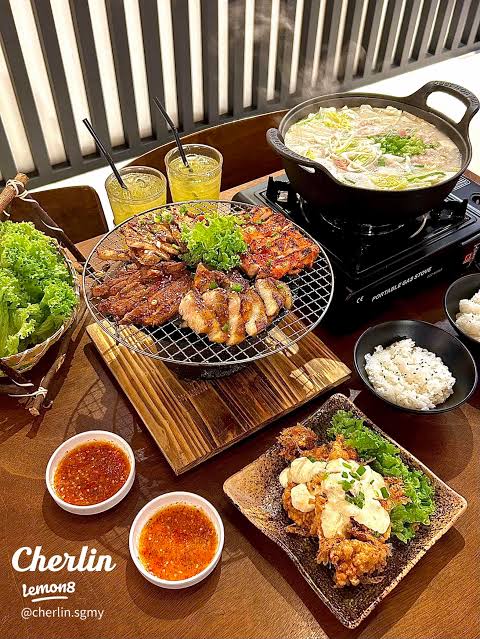 Korean BBQ spread at Hanam BBQ: grilled meats on a rack, a bubbling soup pot, rice and lettuce