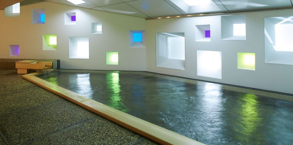 A modern indoor hot-spring bath with colourful square light windows set into the walls