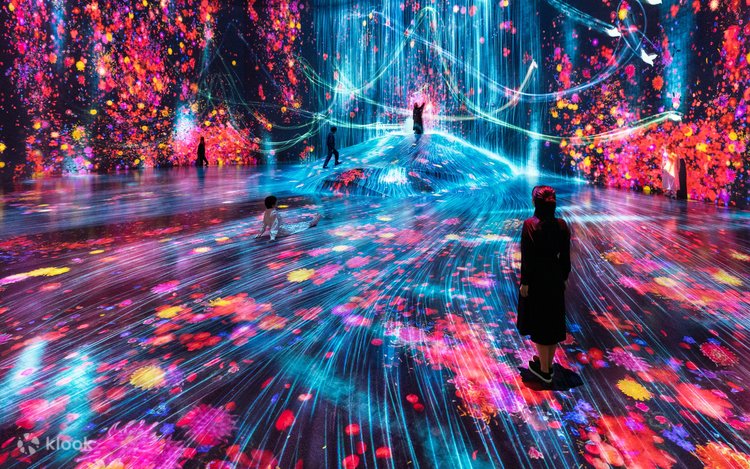 Dark room with projected flowers and streaming blue light and visitors at teamLab Borderless