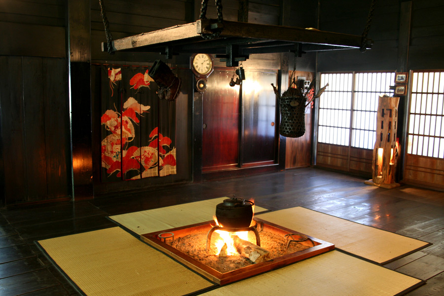 A sunken irori hearth with a kettle over an open fire inside a gassho-zukuri house