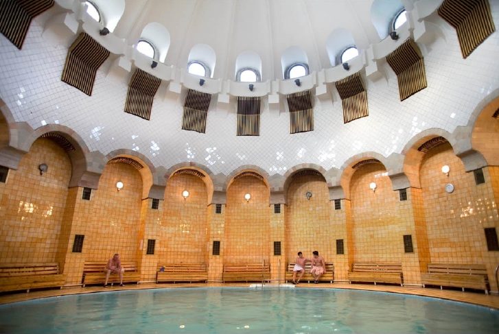 Interior of a domed thermal bathhouse with tiled arches and a circular pool
